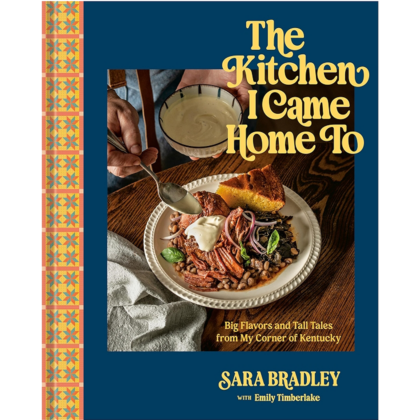 Book cover for 'The Kitchen I Came Home To' by Sara Bradley with Emily Timberlake, featuring a dark blue background, a vertical patterned spine stripe, and a central food photograph of a plated meal with corn on a wooden table.