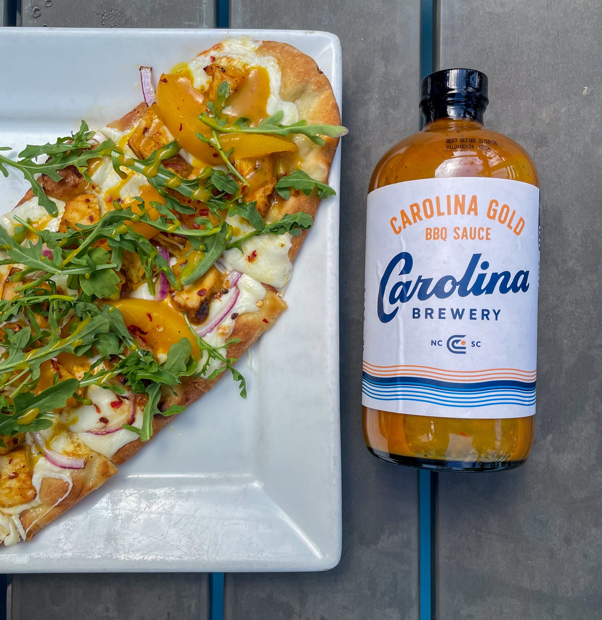 a peach flatbread next to a bottle of Carolina Brewery bbq sauce