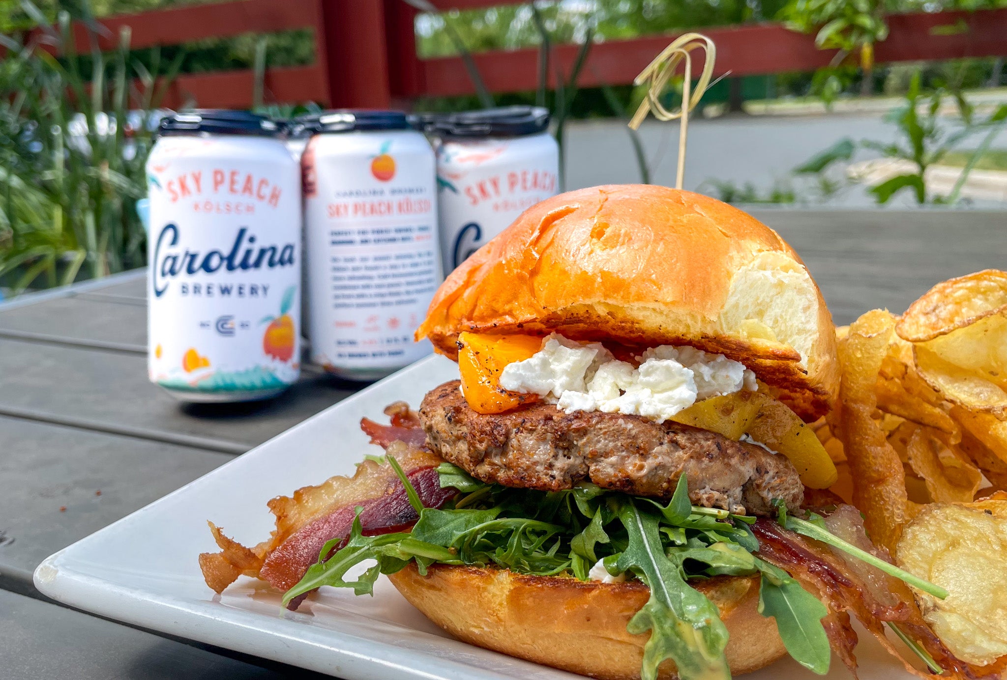 a large burger with chips in front of Carolina Brewery's new peach beer