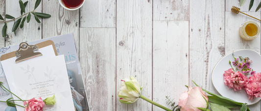 An image of flowers on a gray, plank table, along with a clip board and coffee for the Marketplace Moms' Ideal Mother's Day