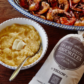 A bowl of grits and a bowl of shrimp with a bag of Charleston Favorites Stone Ground Yellow Grits beside them. 