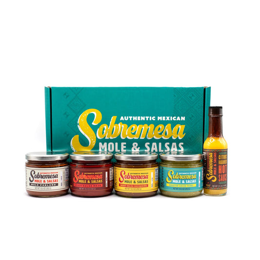 Collection of Sobremesa mole and salsas products including jars and a bottle on a white background.
