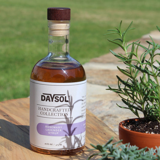 Bottle of Daysol Rosemary Lavender Syrup on a wooden surface with plants in the background