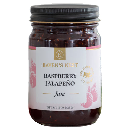 A jar of "Raven's Nest Raspberry Jalapeño Jam" with a white label featuring the brand logo